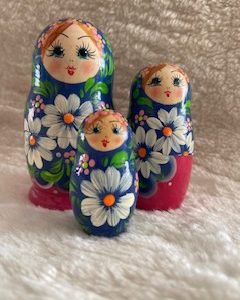 matroesjka met 3 verschillende poppetjes. blauw met roze. groene blaadjes en witte bloemetjes.